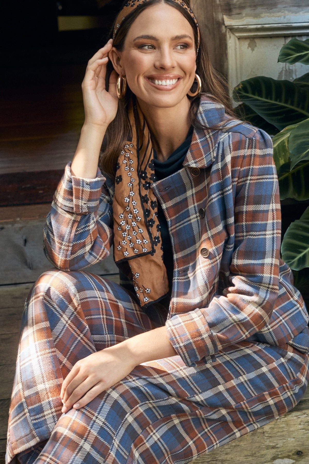Fashion model wearing a dress, posing in front of a sunlit backdrop.