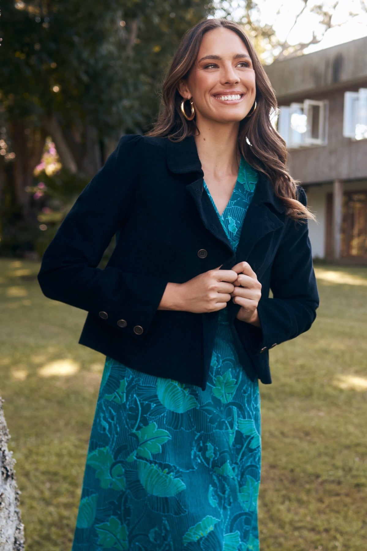 Model in a flowing dress, standing in a field with the wind blowing.