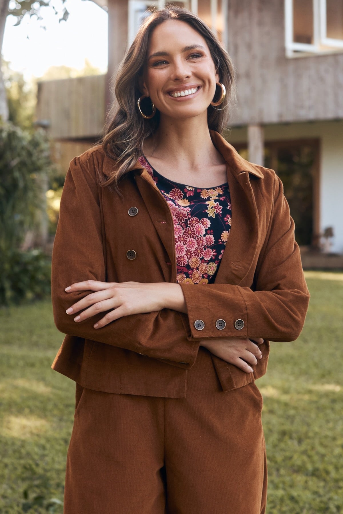 A model confidently posing in a flowy, elegant dress, surrounded by nature and bathed in soft sunlight.