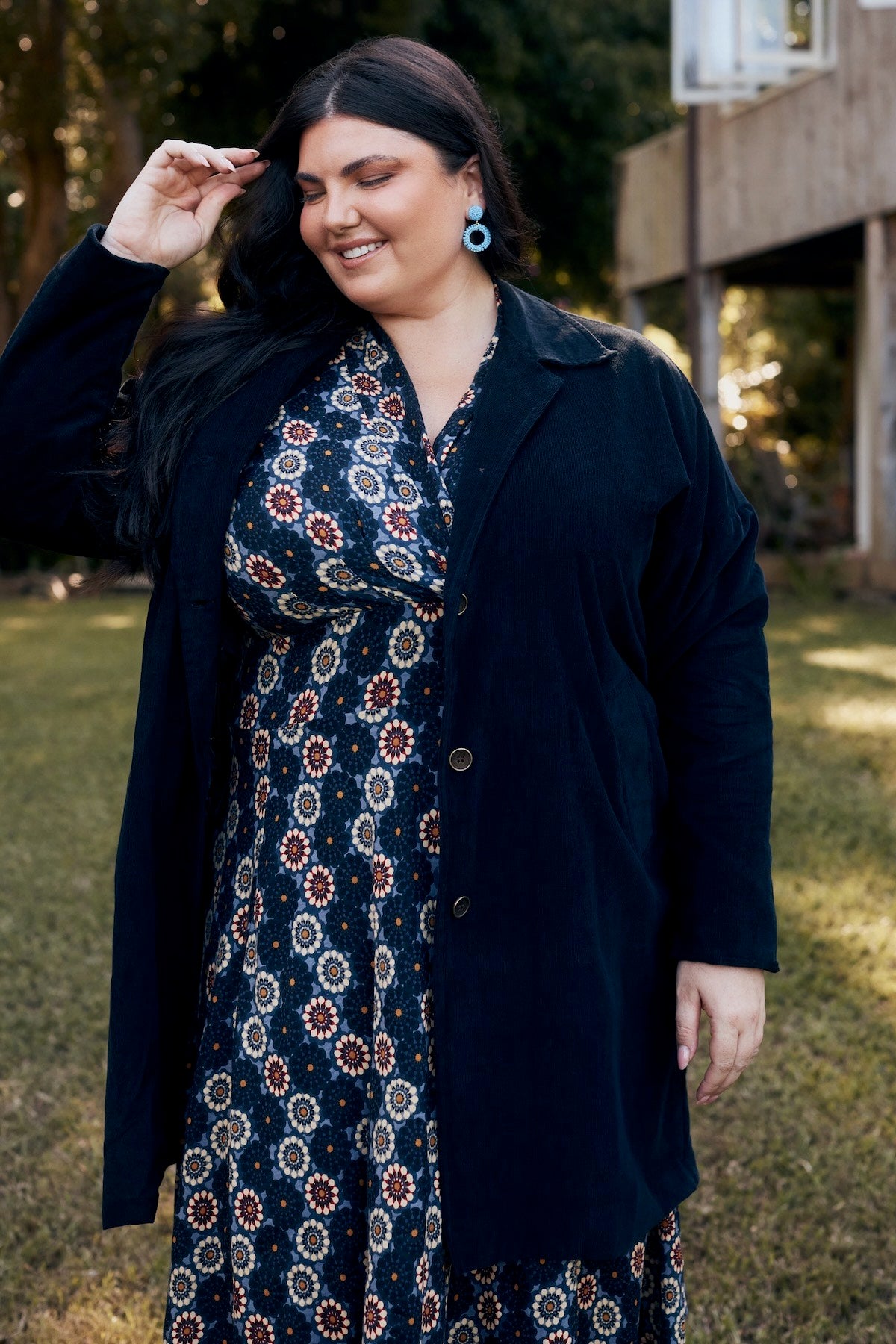 A model confidently posing in a flowing dress, surrounded by nature, with the fabric gently swaying in the breeze.
