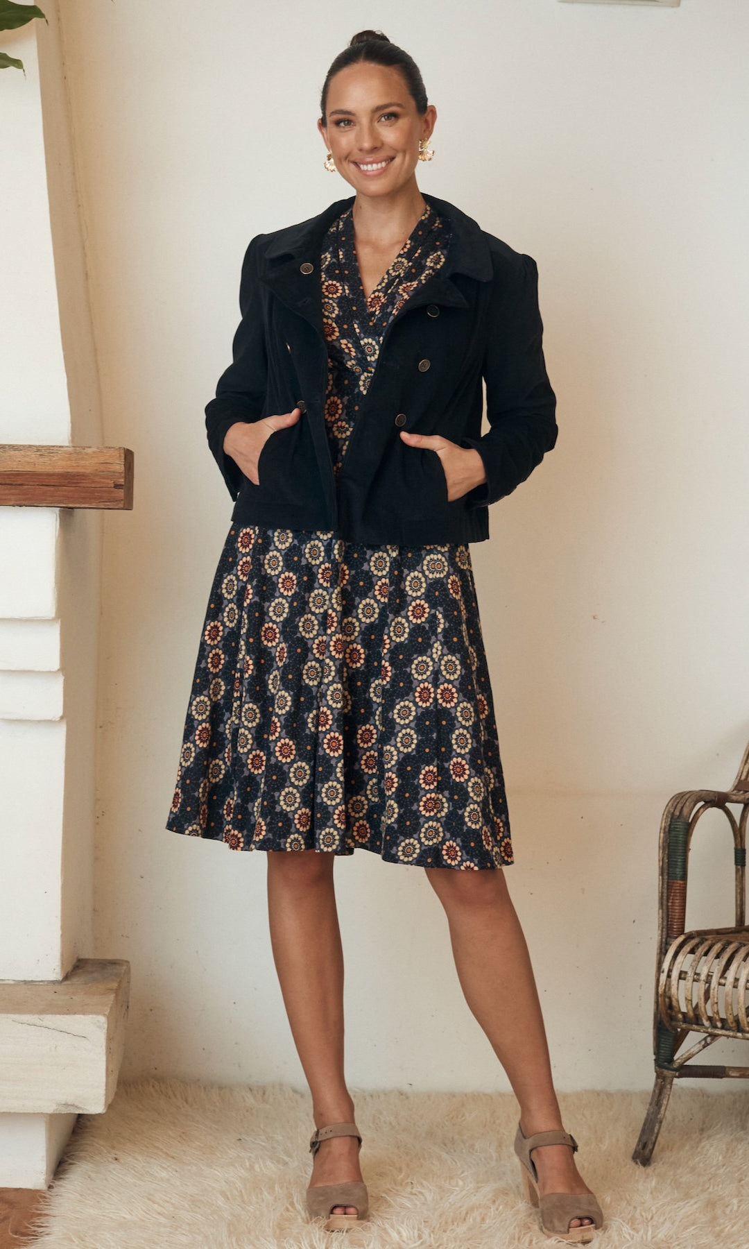 Woman wearing a floral print dress, posing outdoors in natural lighting.