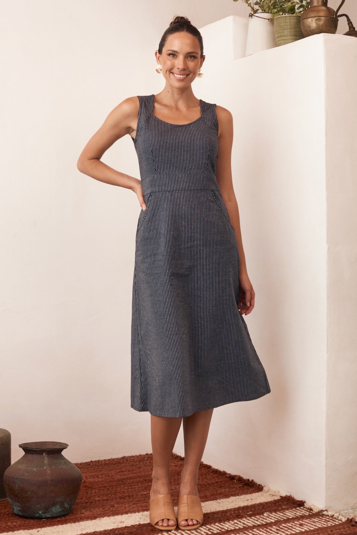 Model wearing a long-sleeve floral print dress, standing in front of greenery.