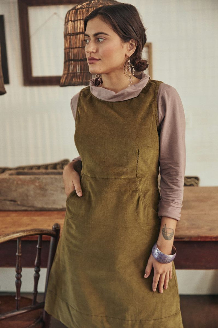 A light, breezy dress hanging on a hanger, with its natural texture and soft hue glowing in the gentle light.