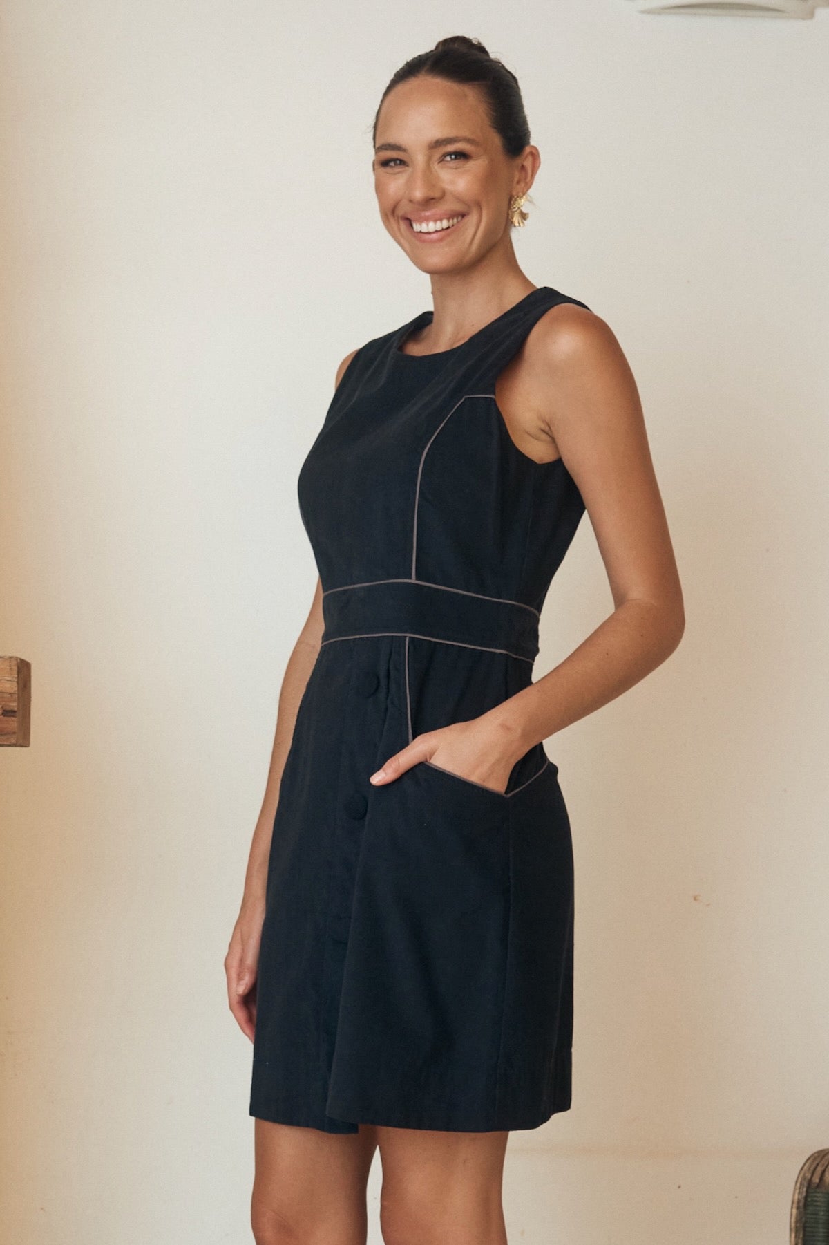 Model wearing a tartan print dress, posing in front of a sunny backdrop.