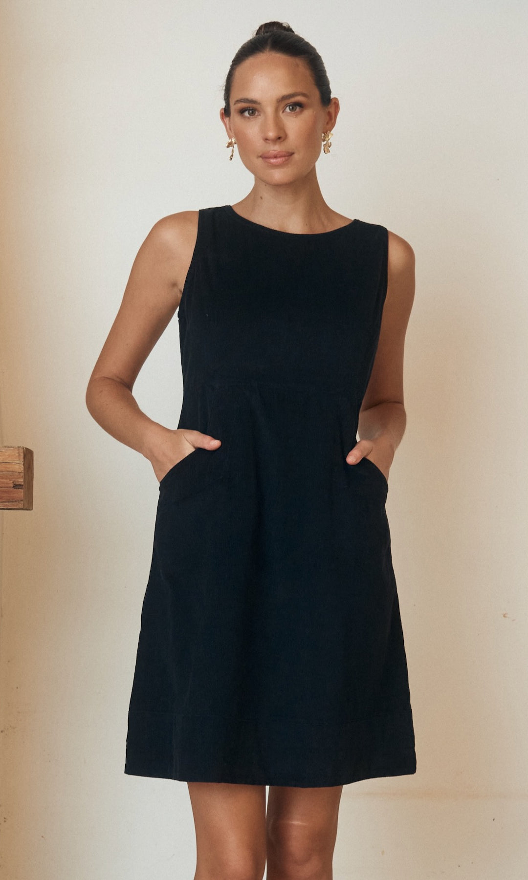 Woman wearing a floral dress, posing against a minimalist outdoor backdrop.
