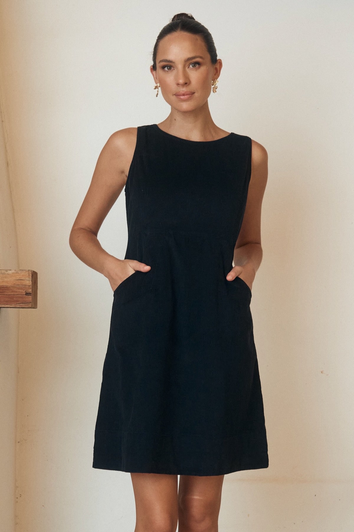 Woman wearing a floral dress, posing against a minimalist outdoor backdrop.