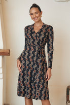 Model in a long-sleeve floral print dress, posing against a rustic background.